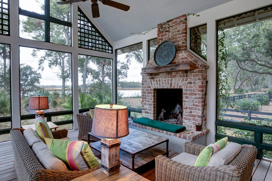 Luxurious three season screen porch with fireplace, looking out onto waterfront property.