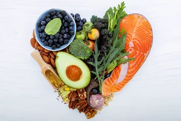 Poster Heart shape of ketogenic low carbs diet concept. Ingredients for healthy foods selection on white wooden background. Balanced healthy ingredients of unsaturated fats for the heart and blood vessels. © kerdkanno