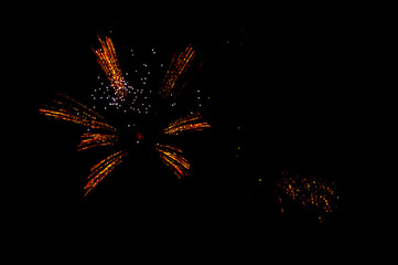 Yellow and red fireworks in the shape flower on the left side on a black background.