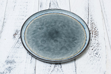 Plate on white scraped wooden background side view