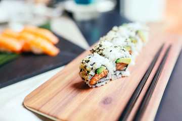 Japanese sushi food. Maki ands rolls with salmon, shrimp, crab and avocado on wooden desk. Top view of assorted sushi, all you can eat menu. Healthy eating concept. Selective focus