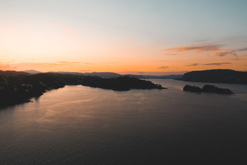Drone shot of sunset in Bergen, sun reflection in water and silhouette mountains