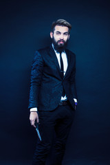 young pretty modern hipster business man with beard standing on black background, fashion style hairstyle