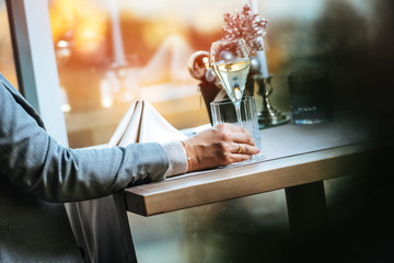 Female sitting by the table in restaurant with a champagne glass . During late evening, high iso image.