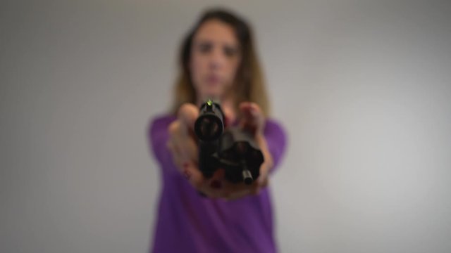 Woman out of focus holding a self defense handgun and checking it for ammo