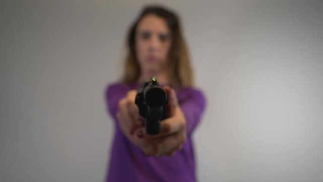 Woman out of focus, gun in focus and handling large black handgun