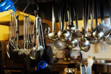 Different type of metal kitchen tools hanging.
