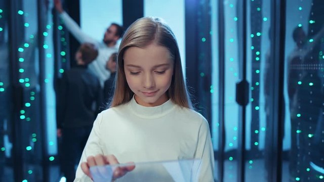 Young beautiful girl IT specialist working on transparent graphics tablet running maintenance programs in server cabinet. Kids in data center.