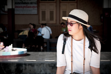 Asian tourists wear white shirts and hats and wait for the train at the station.