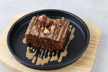 Chocolate and Date cake with nuts on black and wood plate on a white texture background - Close up