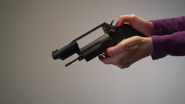 Close up of female with painted red nails, cocking and pulling handgun trigger