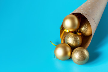 Golden Christmas balls spilled out from a package of kraft paper on a blue background. Christmas balls. Copyspace.