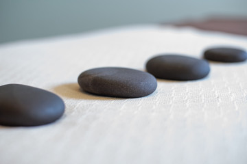 Black massage stones lined up on a massage table