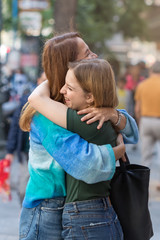 Fototapeta premium Happy mother and teenage daugher hugging each other on the steet outdoors.