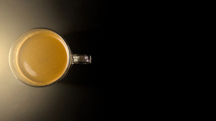 Morning coffee on a black table with fair light on the left.