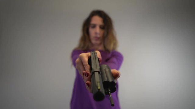 Woman out of focus, gun in focus and checking revolver for bullets