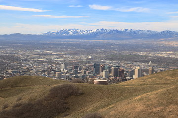 Hikers walk on the trails in the Wasatch Mountain foothills near Salt Lake City with the snowcapped Oquirrh mountains in the background in early spring