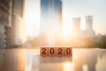 Wooden word number 2020 with sun light on blurred city scape and copy space for text using as background business investment, new year, real estate, property concept.