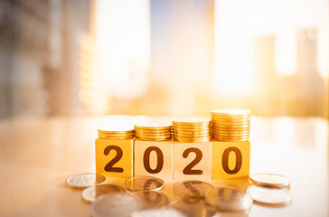 Wooden number 2020 with stack of coins on blurred city scape and copy space for text using as background business investment, new year concept.