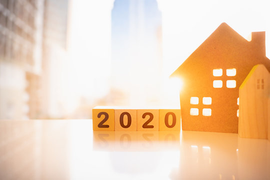 Wooden house with wood number 2020 on blurred city scape and copy space for text using as background business investment, new year, real estate, property concept.