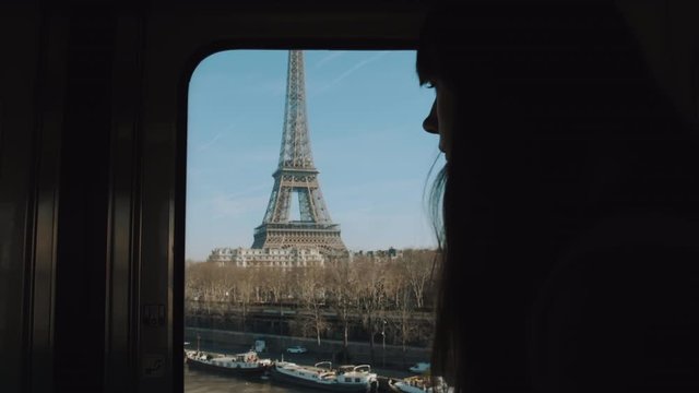 Silhouette of young woman riding metro train at Paris, looking at Eiffel Tower and river Seine in the window slow motion