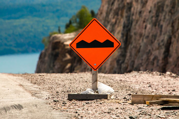 Bump or uneven pavement on the road ahead orange sign on the ground in selective focus view,...