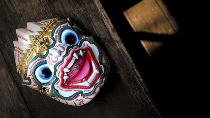 Top view of Thai traditional Hanuman actor's mask( Khon mask) on wooden table with blurred sunlight...