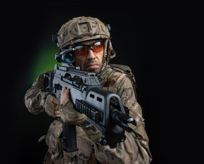 Fototapeta premium a male soldier in military clothes with a weapon on a dark background