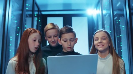 Curious children using a laptop program inside server cabinet, looking excited of exploring technology and computer science, having fun educational tour at database. Smart young team of data center. - Powered by Adobe