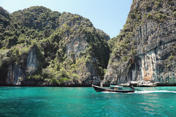 Boat moving in beautiful crystal clear water at Phi Phi island near Phuket, Thailand.
