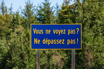 Blue Information Road Sign with french yellow writing, you cannot see not to exceed, on rural country roadside, trees background, Ontario, Canada