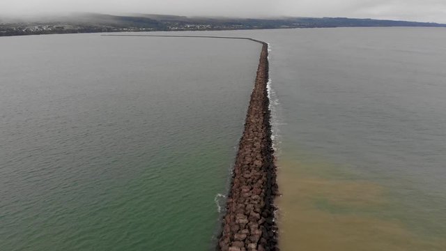 aerial shot of hilo breakwater on the big island, rain in background
