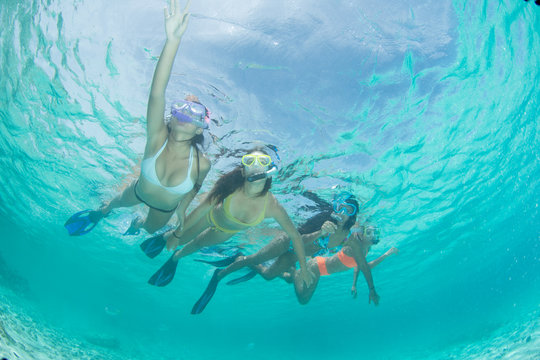 Four Young girls friends snorkeling in blue clear waters at caribbean turquoise island 