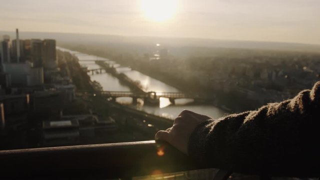 Close-up shot of male hands on observation deck fence at Eiffel Tower, Paris, epic sunset sky view panorama slow motion