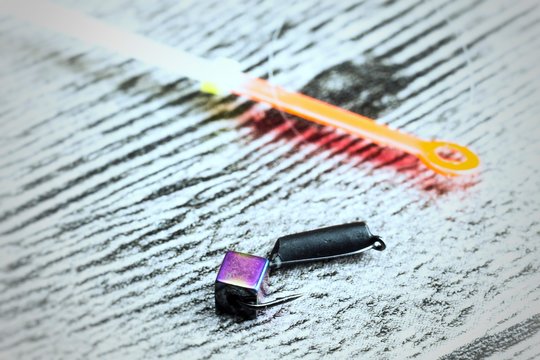 Winter fishing lure on the grey wooden table