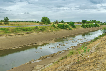 Fototapeta na wymiar Irrigation canal in concrete wall Send water from the reservoir to the agricultural area of ​​the farmer that is dry in the rainy season of Thailand. Environmental disaster in agriculture.