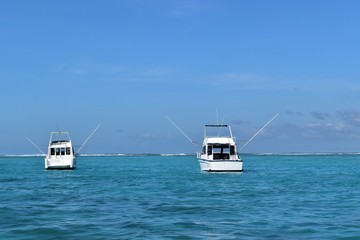 Two beautiful boats with booms deployed to deport fishing lines. Fishing game, sea vacation background.