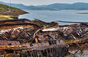 Cemetery of old ships on the shore of the Barents Sea at low tide - the wrecks of ships, water and algae