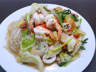 Thai food style, Selective focus of spicy vermicelli salad with seafood and mixed vegetable isolated on white plate as a background, This food is most popular Thai food (Mung Bean Noodle Spicy Salad)