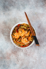 Chahan fried rice with egg, vegetables and shrimp on the lighter concrete background. Vertical photo. top view.