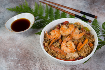 Tyahan with egg, vegetables and shrimp on a light concrete background with a fern leaf and soy sauce. Horizontal photo.