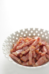 Fried bacon in white bowl on white background with copy space