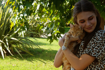 Young attractive girl with a cat in the park.