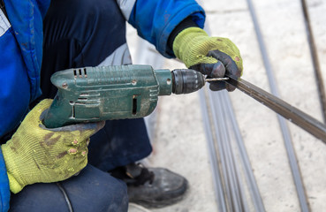 Worker drills a hole in the plastic at a construction site