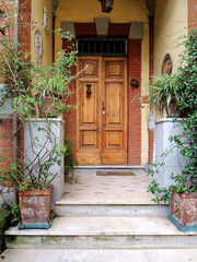 View of the beautiful exterior of the house and the front door on the street of Florence. A cozy image of the home where you want to return. Green plants and flowers in terracotta pots on the steps.