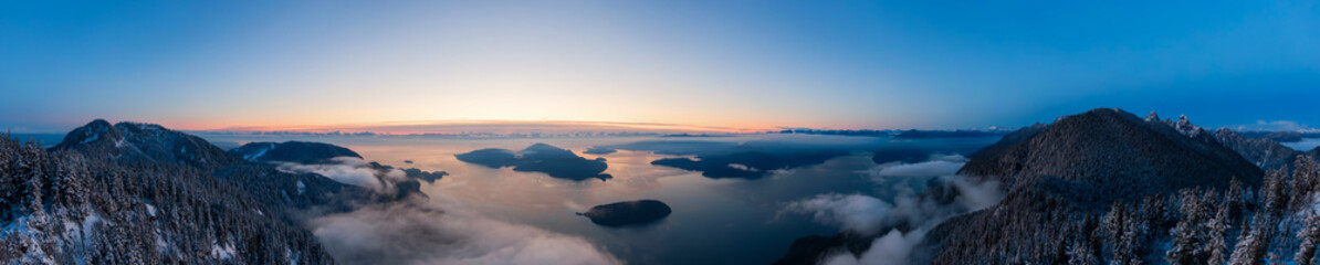 Fototapeta premium Aerial Panoramic View of Canadian Mountain Landscape on the Pacific Ocean Coast during a colorful sunset. Taken in Howe Sound near Vancouver, British Columbia, Canada.