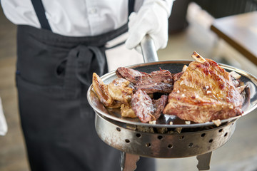The waiter is holding a plate Various grilled meat set. Barbecue restaurant menu, a series of photos of different meats.