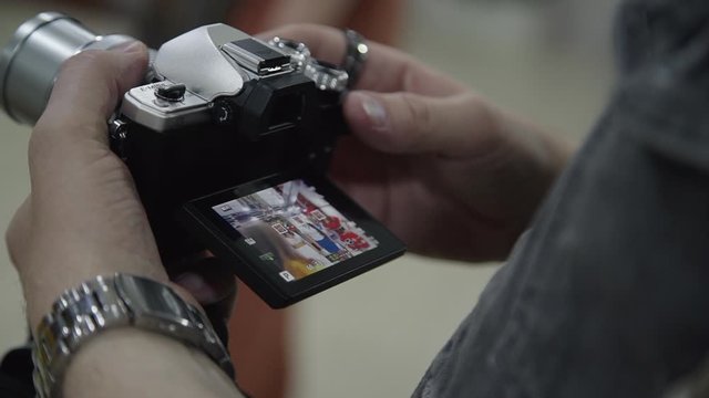 Male photographer is taking pictures on his carema, close up of hands. Man is looking ot the screen of expensive equipment. checking screen. digital, display, model concept