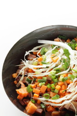 Chopped cabbage, carrot, spring onion, bacon on frying pan
