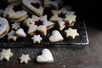 Biscotti natalizi Linzer fatti in casa. Biscotti con pasta frolla e marmellata di lamponi su sfondo scuro.